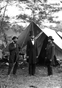 Allan Pinkerton, President Lincoln, and Major John A. McClernand in an 1862 photo by Alexander Gardner following the Battle of Antietam. Pinkerton was the head of Union Intelligence Services then. It was alleged that, in 1861, his Pinkerton Detective Agency uncovered an assassination plot against the president in Baltimore on his way to the inauguration. Thanks to Pinkerton's warning, Lincoln changed his travel itinerary and the plot was foiled. On the 3-story Chicago building of the Pinkerton Detective Agency, their logo, a black-and-white eye, says "We Never Sleep." This was the origin of the slang term for detective "private eye." 