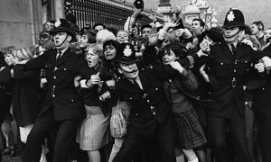 Beatlemania. October 1965, London, England, UK.  Policemen struggle to restrain young Beatles fans outside Buckingham Palace as The Beatles receive their MBEs (Member of the British Empire) in 1965.