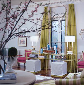 A modern room with touches of Schiaparelli pink in the two chairs and flowers in foreground