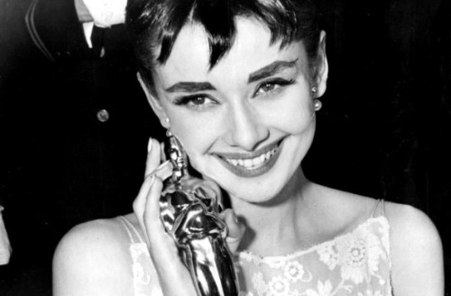 1953 Audrey Hepburn grins upon receiving her Oscar for "Roman Holiday."