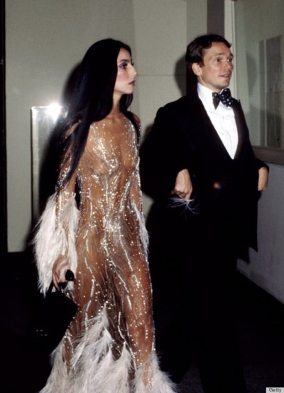 Cher and her designer Bob Mackie arrive at a Met gala, 1974. She is wearing a Mackie bodysuit embroidered with feathers and crystals. Mackie said of his muse, "She had such an unbelievable body. She could wear anything." This outfit would be featured on the cover of "Time" magazine the following spring. (1)